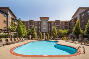 Omaha apartment for rent - a swimming pool with chairs around it in front of an apartment building