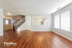 Plainfield house for rent - A spacious room with wooden flooring and a staircase leading to another level.