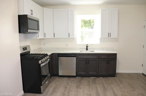 Philadelphia apartment for rent - an empty kitchen with black appliances and white cabinets