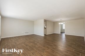 Port Richey house for rent - A spacious room with wooden flooring and white walls, branded with "FirstKey Homes".