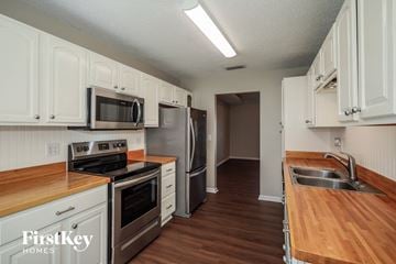 Jacksonville house for rent - a kitchen with white cabinets and stainless steel appliances