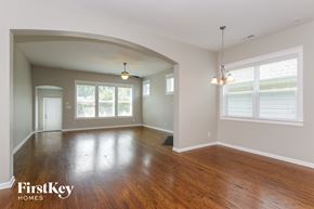 Belmont house for rent - A spacious room with wooden floors and a large arched doorway.