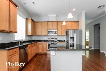 Belmont house for rent - A modern kitchen with wooden cabinets and a black countertop.