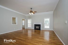 Kernersville house for rent - an empty living room with a ceiling fan and a fireplace