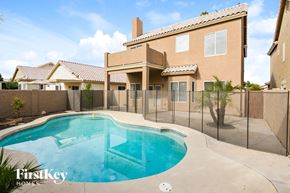 Peoria house for rent - a pool in front of a house with a fence around it