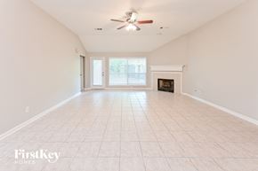 Houston house for rent - A spacious room with a fireplace and a ceiling fan.