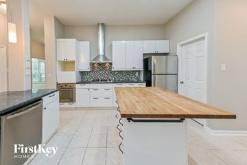Houston house for rent - A kitchen with a wooden counter top and white cabinets.