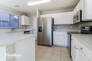 Buckeye house for rent - a kitchen with white cabinets and a stainless steel refrigerator