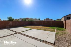 Buckeye house for rent - a backyard with a fence and a yard with concrete and grass