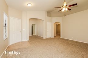 Peoria house for rent - A spacious room with a ceiling fan and carpeted floor.