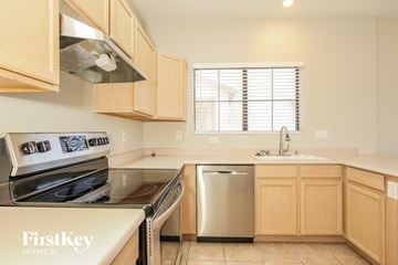 Peoria house for rent - A kitchen with wooden cabinets and a stainless steel dishwasher.