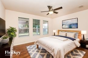Fort Worth house for rent - A bedroom with a bed, a ceiling fan, and a painting on the wall.