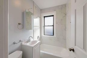 Chicago apartment for rent - a white bathroom with a sink and tub and a window