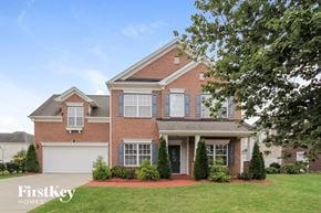 Charlotte house for rent - A brick house with a white garage door and a tree in front.