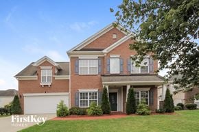Charlotte house for rent - A brick house with a white garage door and a tree in front.