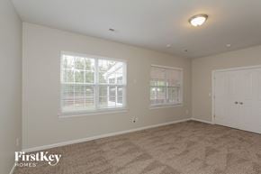 Charlotte house for rent - A room with a carpet floor, two windows with blinds, and a white door.