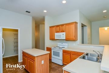 San Antonio house for rent - A kitchen with wooden cabinets and a white fridge.
