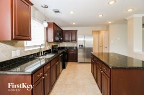 Mckinney house for rent - a kitchen with granite counter tops and wooden cabinets and a stainless steel refrigerator