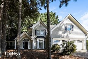 Woodstock house for rent - A house with a garage is surrounded by trees.