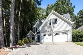 Woodstock house for rent - A two-story house with a garage is surrounded by trees.