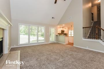 Woodstock house for rent - A spacious living room with a staircase on the right and a kitchen area in the background.