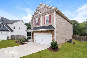 Clayton house for rent - a tan house with a white garage door in front of a green yard