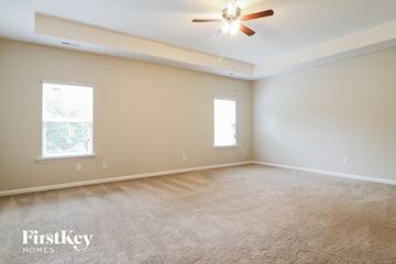Clayton house for rent - a spacious living room with carpet and a ceiling fan
