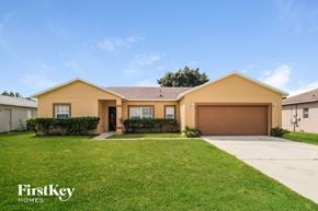 Poinciana house for rent - a yellow house with a lawn and a driveway