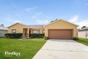 Poinciana house for rent - a yellow house with a garage door and a lawn