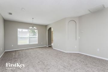 Poinciana house for rent - a spacious living room with white carpet and arched doorways