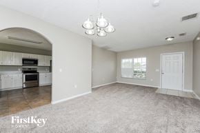 Poinciana house for rent - the living room and kitchen of an open floor plan with white cabinets