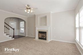 Charlotte house for rent - an empty living room with a fireplace and a ceiling fan