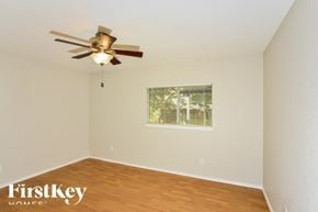 San Antonio house for rent - A room with a ceiling fan and a window with a view of a fence and trees.