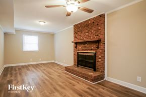 Garner house for rent - A room with a fireplace and a ceiling fan.
