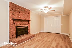 Garner house for rent - A room with a brick fireplace and wooden floors.