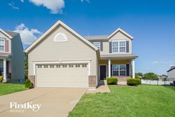 St Charles house for rent - a beige house with a white garage door and a green lawn