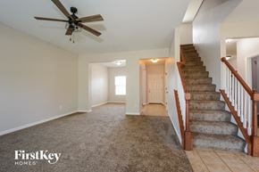 St Charles house for rent - a carpeted living room with stairs and a ceiling fan