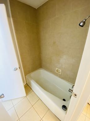 Lafayette house for rent - A white bathtub with a shower head and a white door.