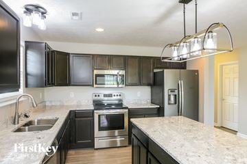 Whitestown house for rent - A kitchen with black cabinets and stainless steel appliances.