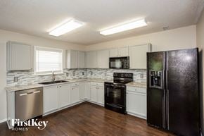 Fishers house for rent - a kitchen with white cabinets and a black refrigerator