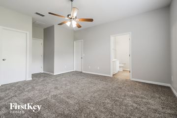 Apopka house for rent - a spacious living room with gray carpet and a ceiling fan