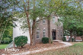 Clemmons house for rent - A brick house with a black door and windows surrounded by trees.