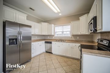 North Charleston house for rent - A kitchen with white cabinets and a stainless steel refrigerator.