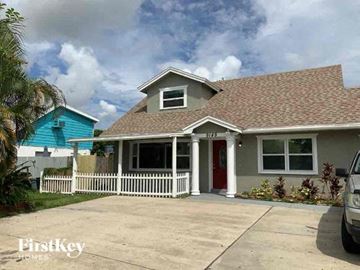 Largo house for rent - a gray house with a white fence and a blue house
