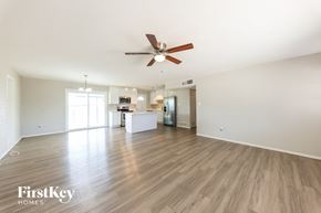 Glendale house for rent - an empty living room with a ceiling fan and a kitchen