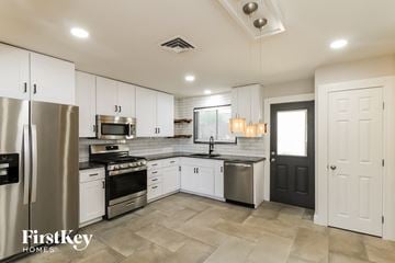 Phoenix house for rent - a kitchen with white cabinets and stainless steel appliances