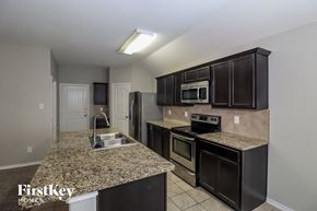 Fort Worth house for rent - a kitchen with granite counter tops and black cabinets and stainless steel appliances