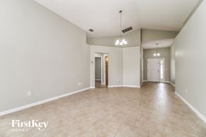 Deltona house for rent - an empty living room and hallway with tile floors and white walls
