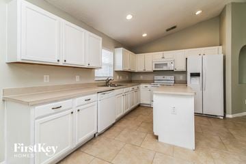 Deltona house for rent - a large kitchen with white cabinets and white appliances