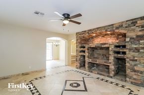 Glendale house for rent - A stone fireplace in a room with a fan on the ceiling.